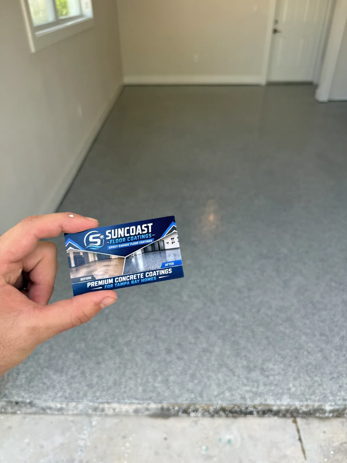 Suncoast Floor Coatings owner holding business card over freshly installed full-flake garage floor