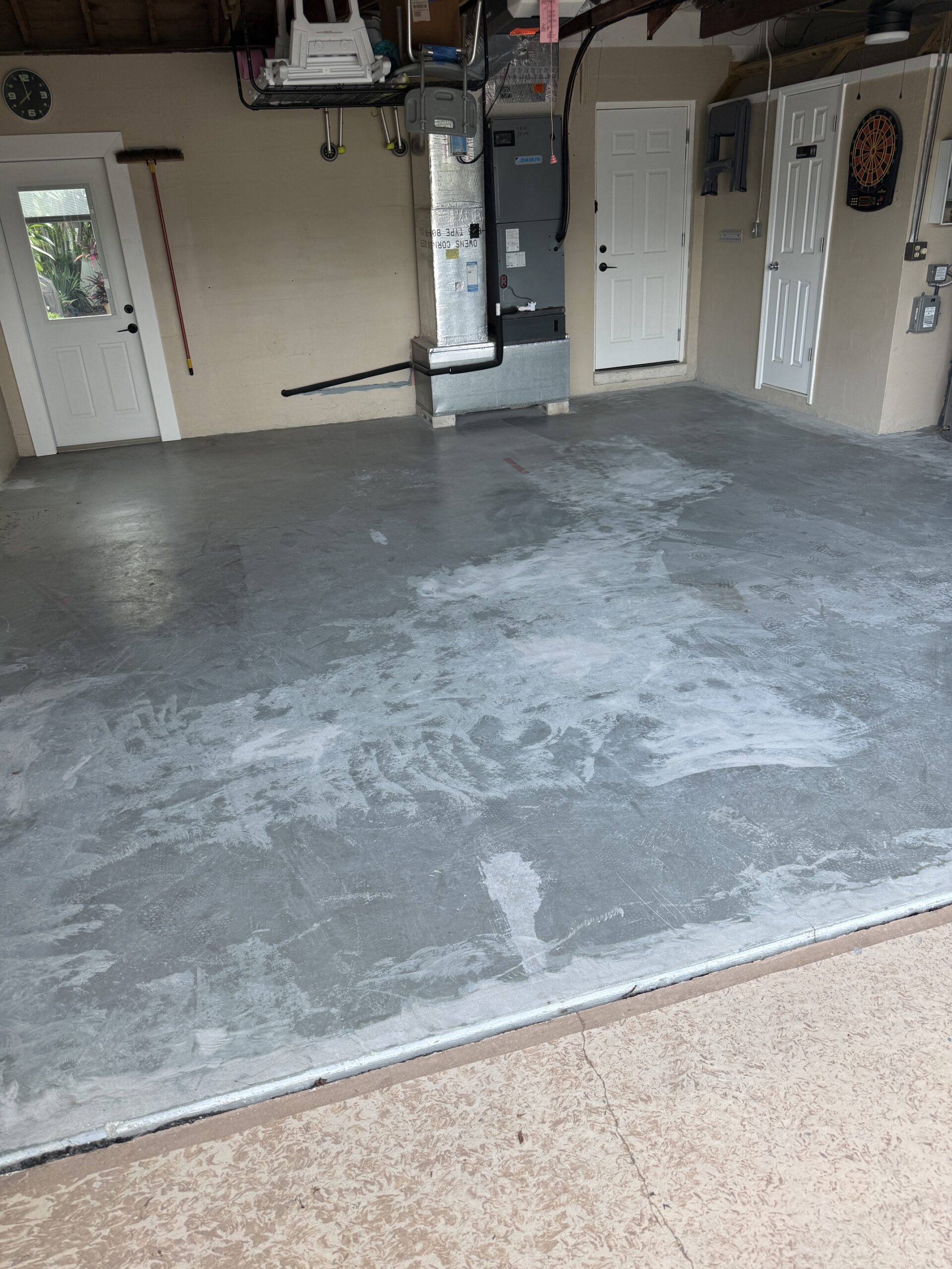 Worn gray two-car garage floor in Seminole before epoxy and Domino flakes