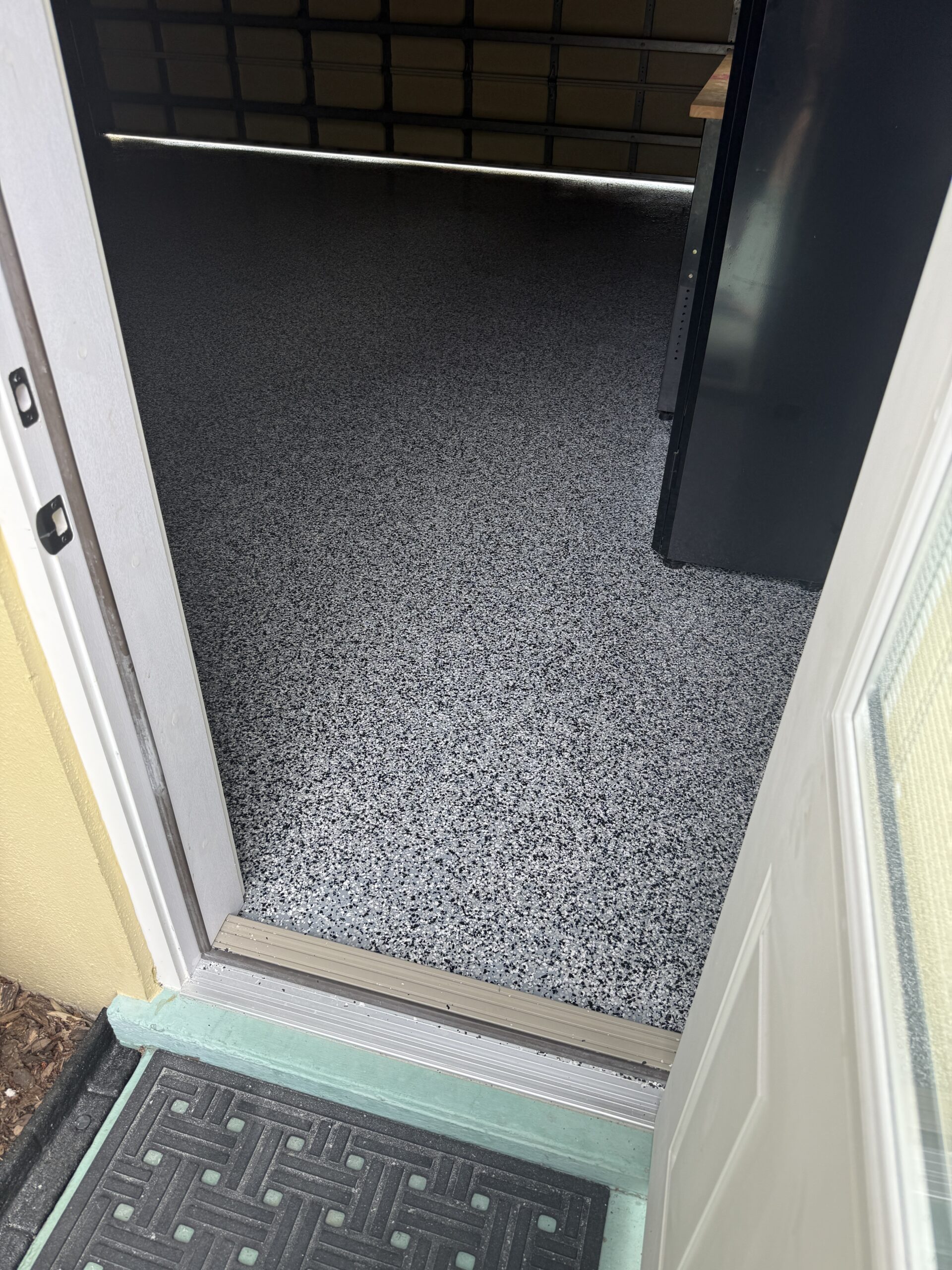 Gray full-flake garage floor coating detail at a doorway threshold